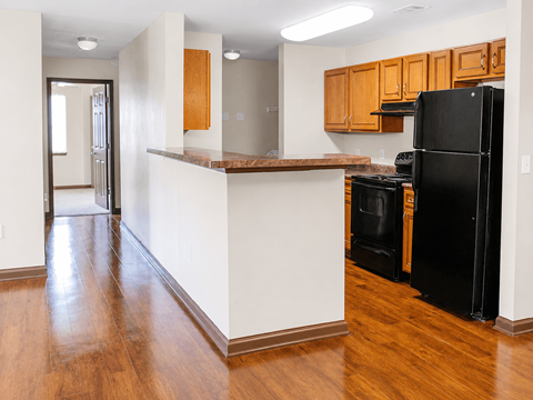 A kitchen with a black refrigerator and wooden cabinets.