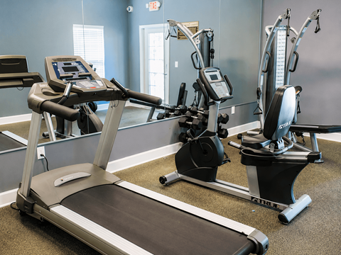 A treadmill and two stationary bikes are in a gym.