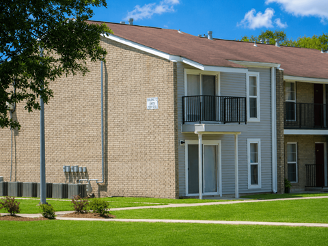 A brick building with a balcony and a sign on the wall.