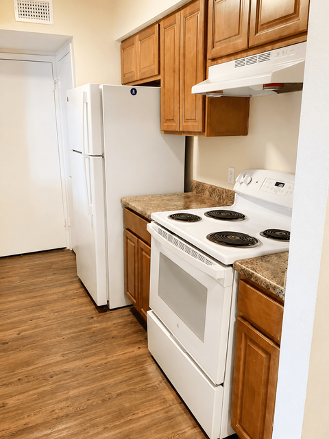 A white refrigerator and oven in a kitchen with wooden cabinets.