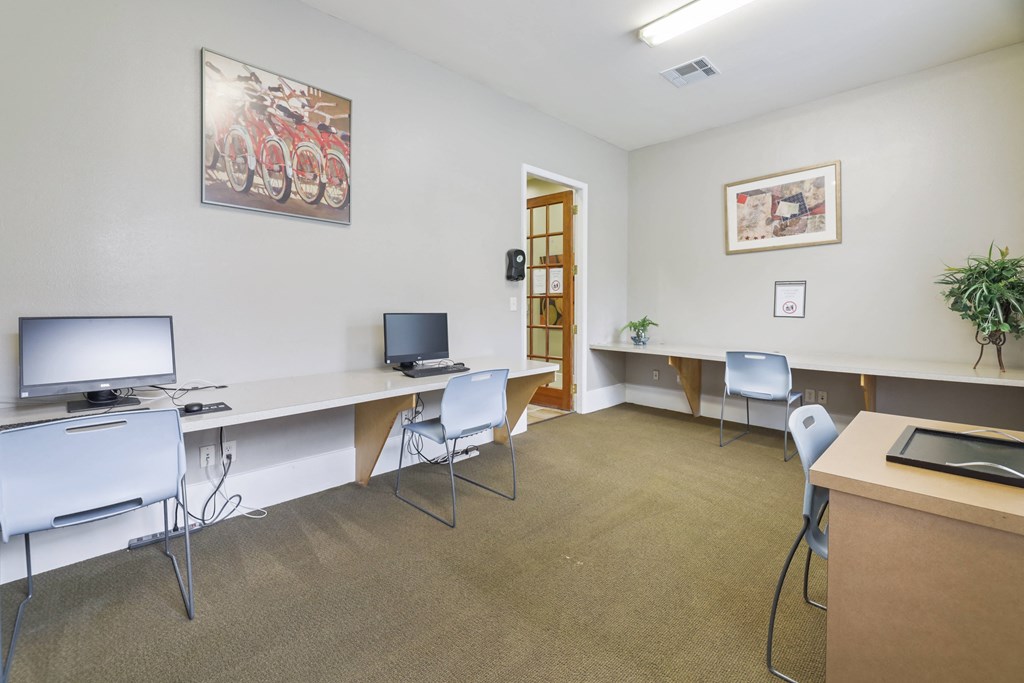 A room with a desk, chairs, and a computer monitor.