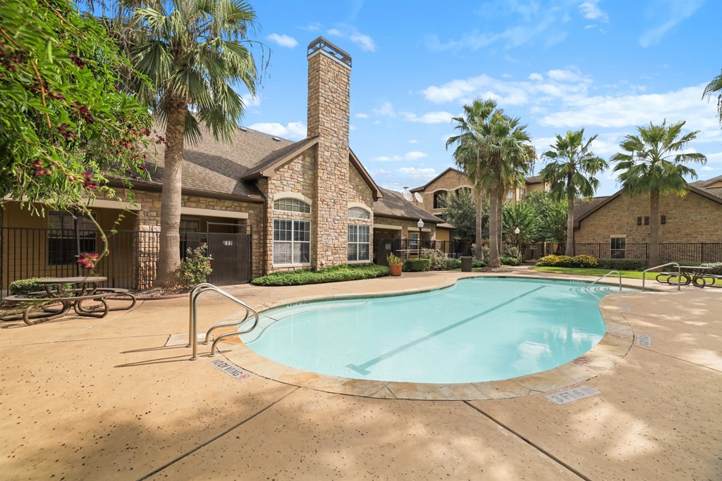 A pool in a backyard with a house and palm trees.