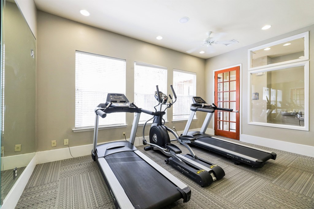 A home gym with a treadmill, elliptical trainer, and stationary bike.