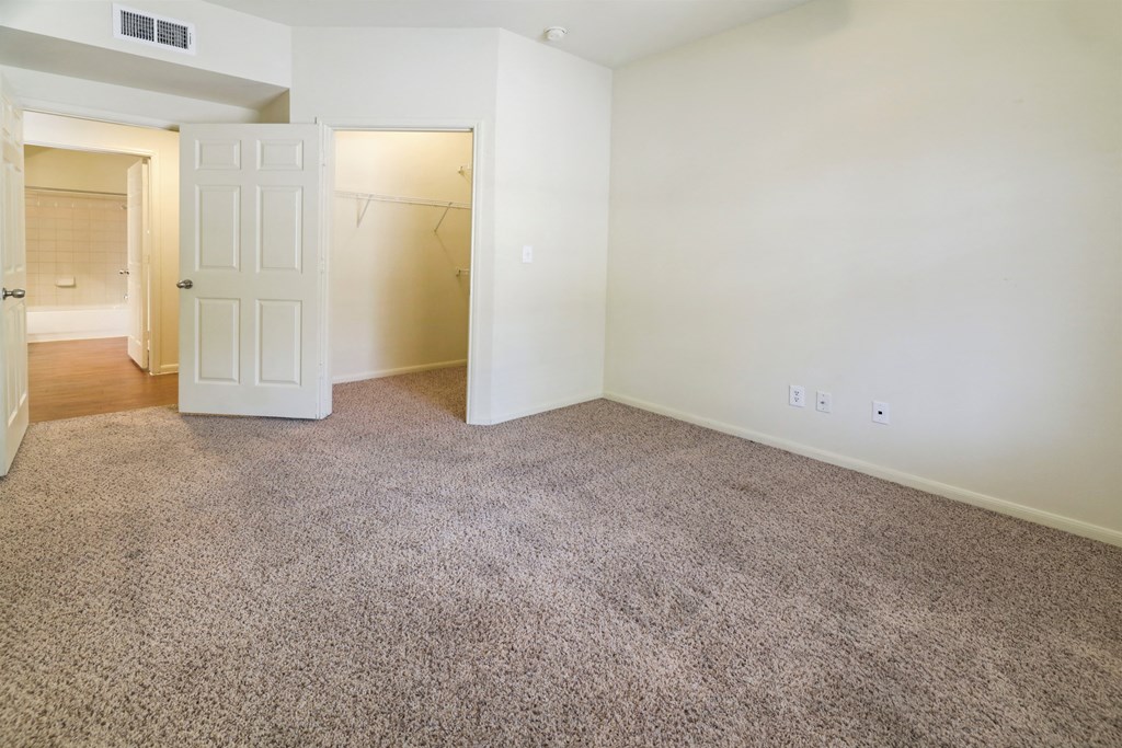 A room with a carpeted floor and two white doors.