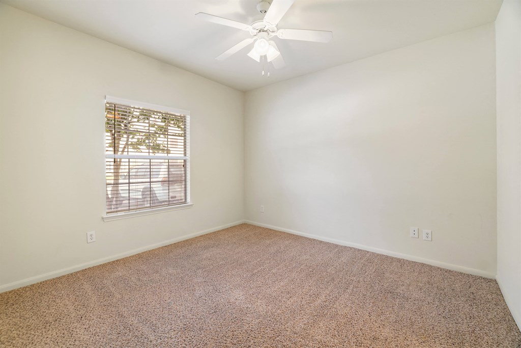 A room with a carpeted floor and a ceiling fan.
