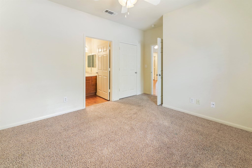 A room with a carpeted floor and a ceiling fan.