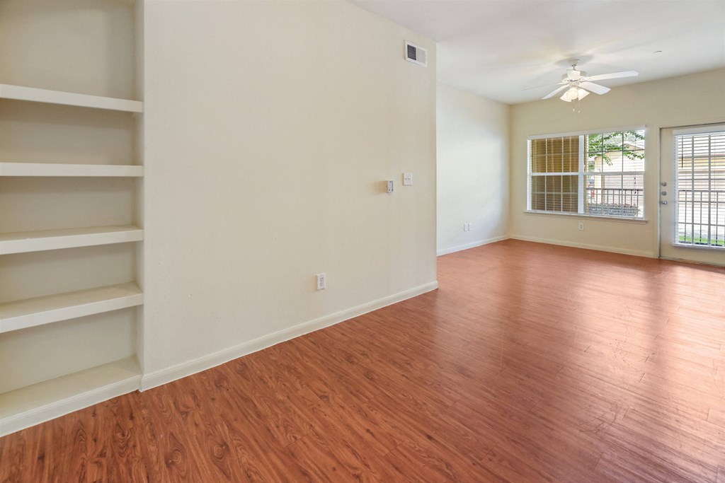 A room with wooden floors and a window with blinds.