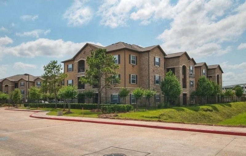 A large brick apartment complex with a parking lot in front.