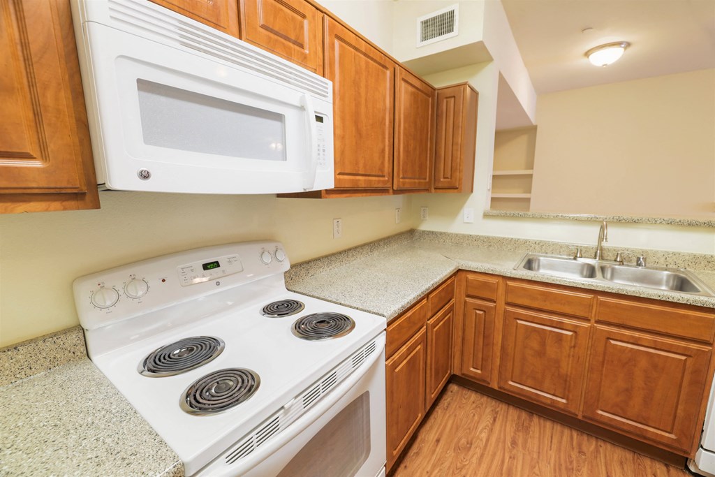 A white stove and microwave in a kitchen with wooden cabinets.