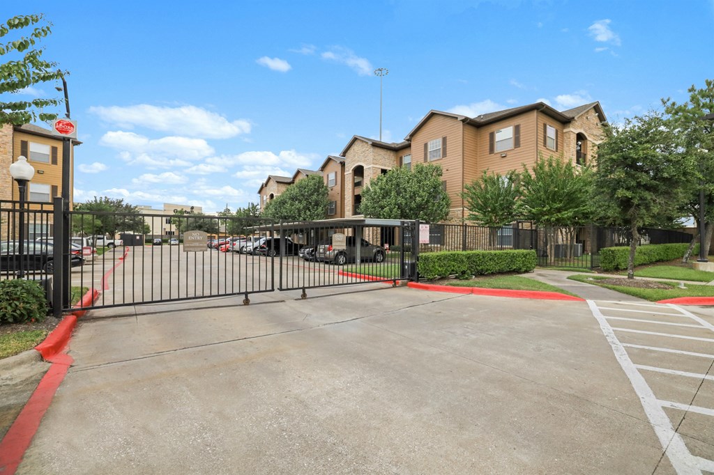 A gated parking lot in front of a building.