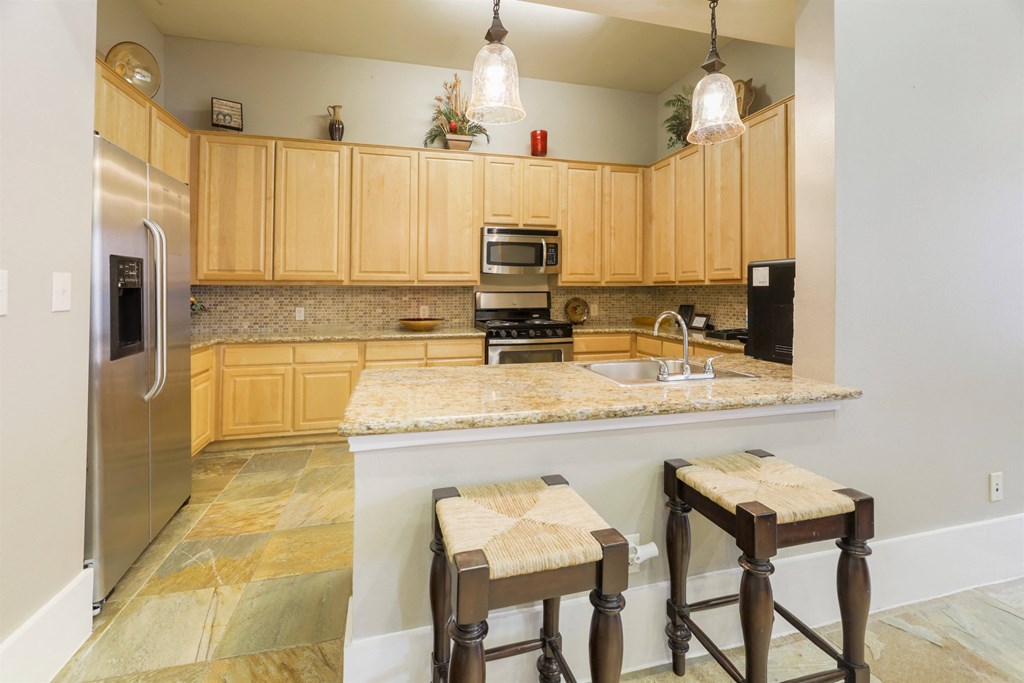 A kitchen with wooden cabinets and a marble countertop.