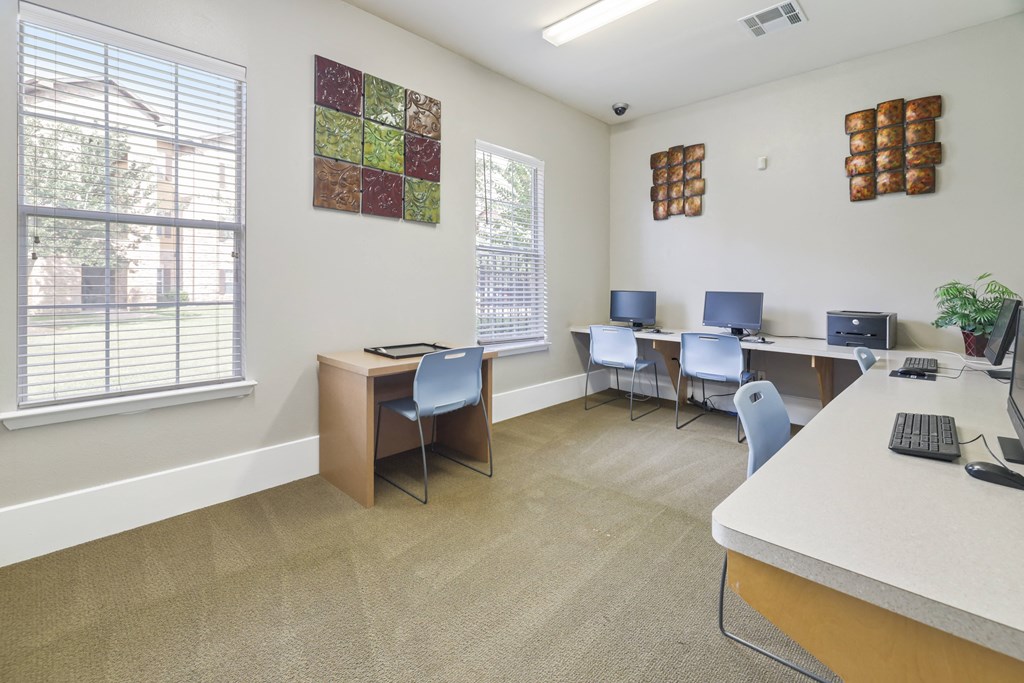 A room with a desk, chairs, and a window.