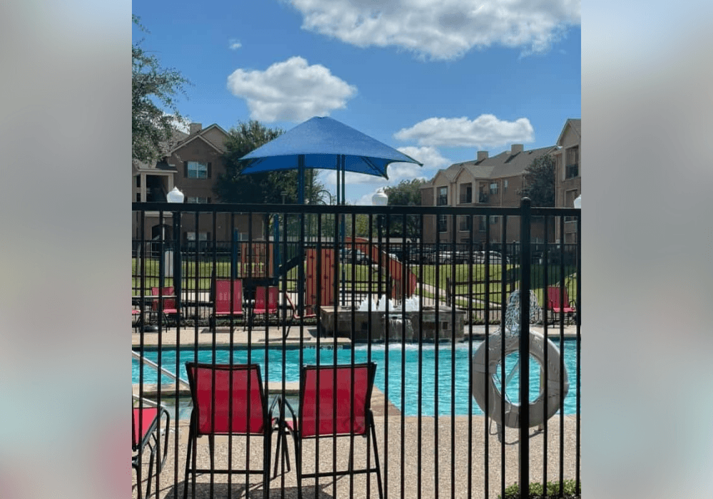 a pool with chairs and a blue umbrella at a resort
