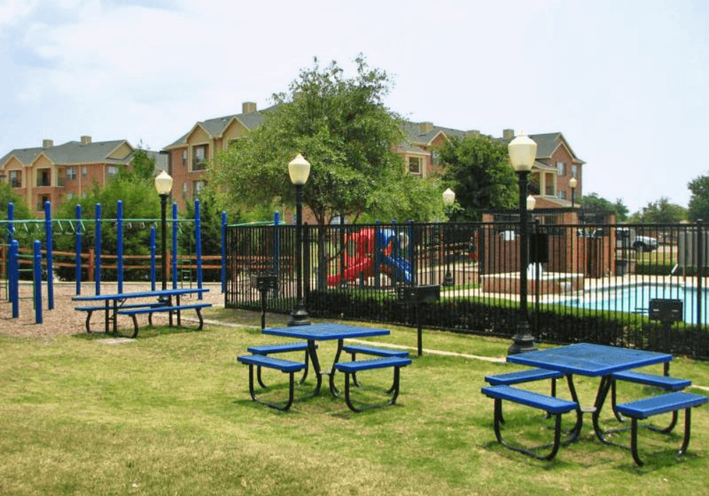 a group of blue picnic tables in front of a pool