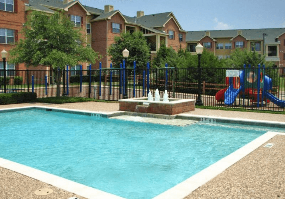 a swimming pool with a fountain in front of an apartment building