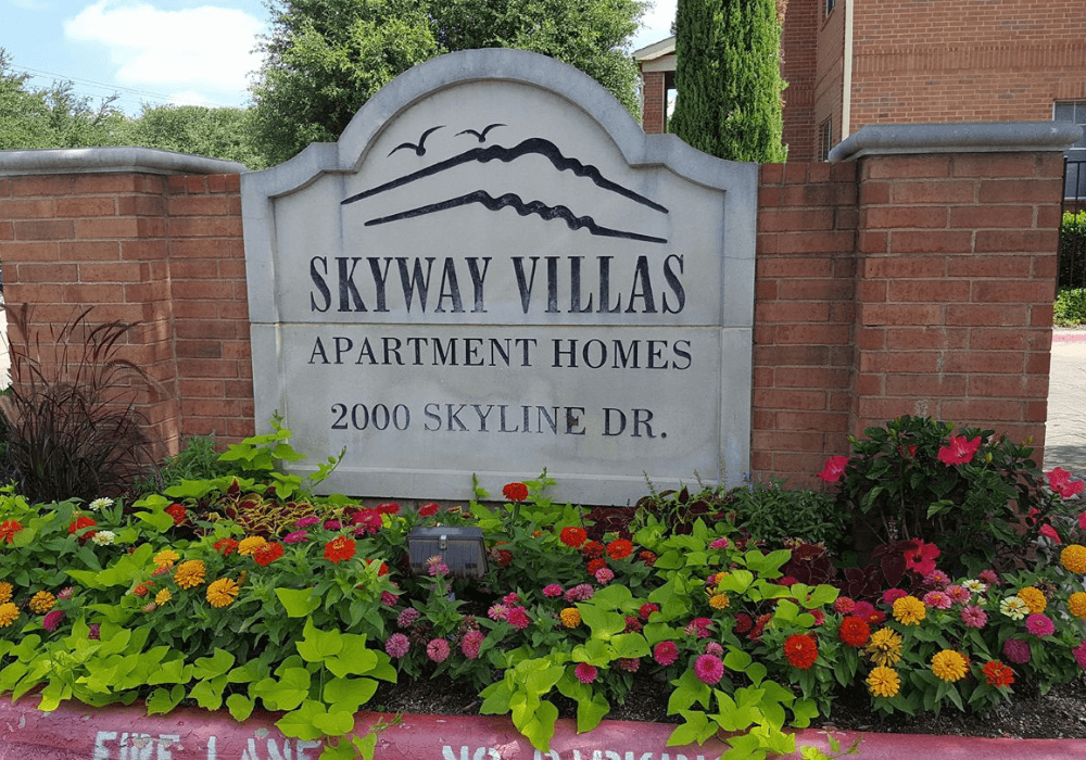 a sign for skyway villas apartment homes in front of flowers