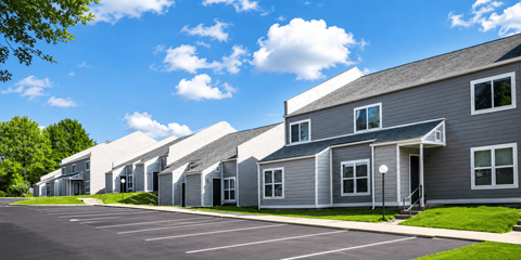 A row of modern houses with grey exteriors and white roofs.