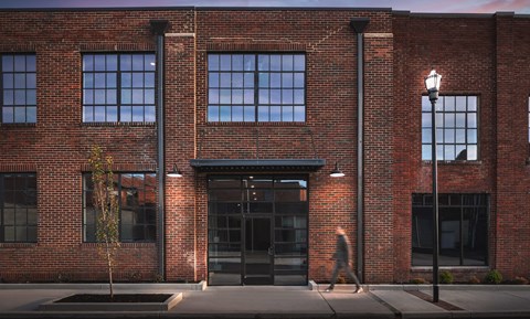 A person is walking in front of a red brick building.