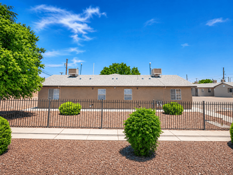 A building with a black fence and bushes in front.