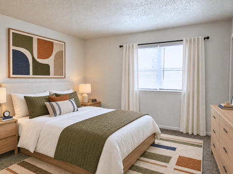 A bedroom with a bed, nightstand, and a painting on the wall.