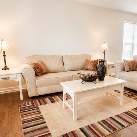 A living room with a white couch, a white coffee table, and a striped rug.