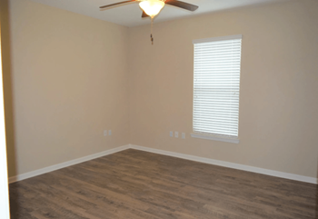 an empty living room with wood floors and a ceiling fan
