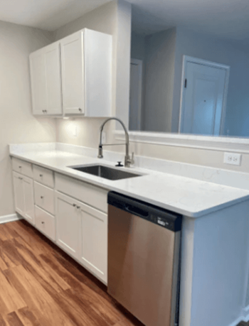 a kitchen with white cabinets and a stainless steel dishwasher