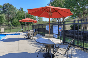 our patio has tables with umbrellas and chairs by the pool