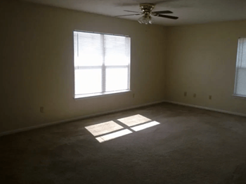 an empty room with a window and a ceiling fan