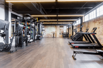 a gym with cardio machines and weights on a wooden floor at The Mill at Prattville, Prattville, AL