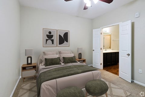 A bedroom with a bed, two lamps, and two framed pictures on the wall.