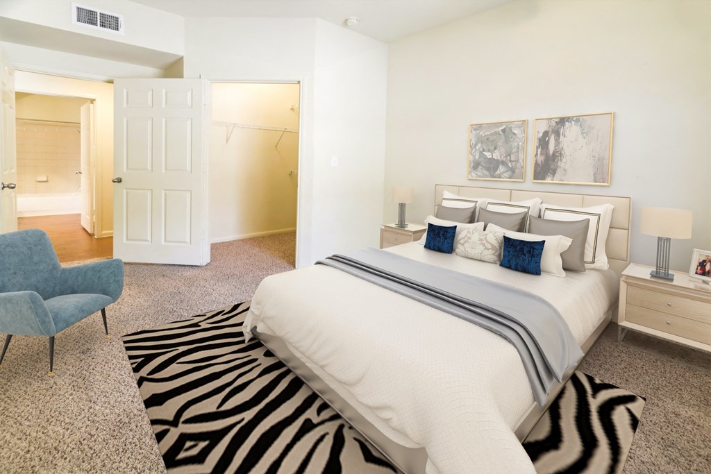 A bedroom with a white bed and a blue chair.
