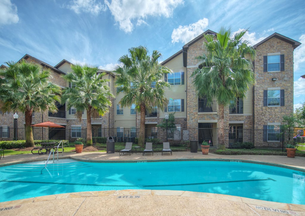 A large apartment complex with a pool in front.