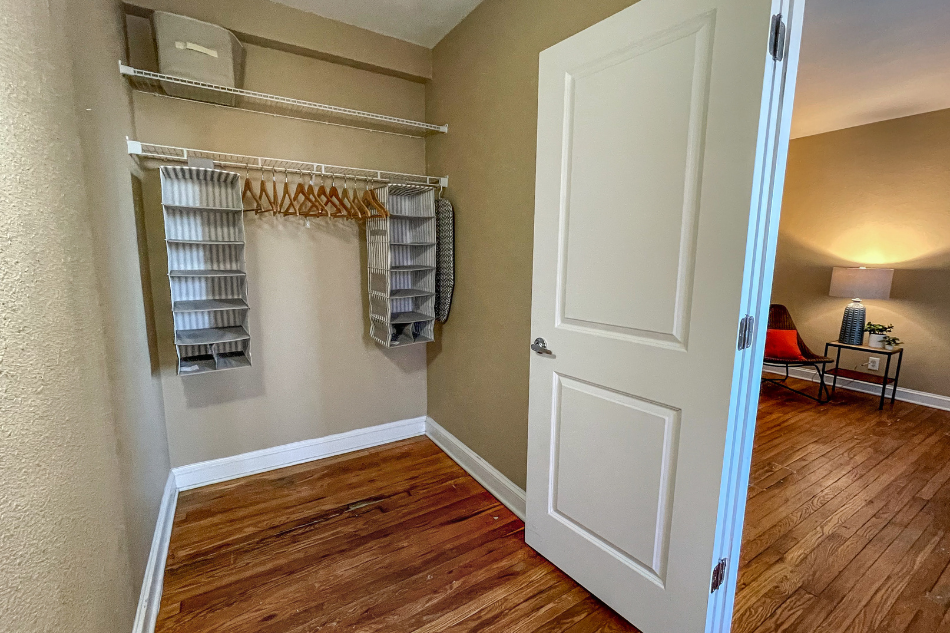 an empty living room with a closet with shelves