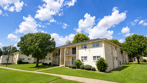 Apartment complex with a green lawn and trees.