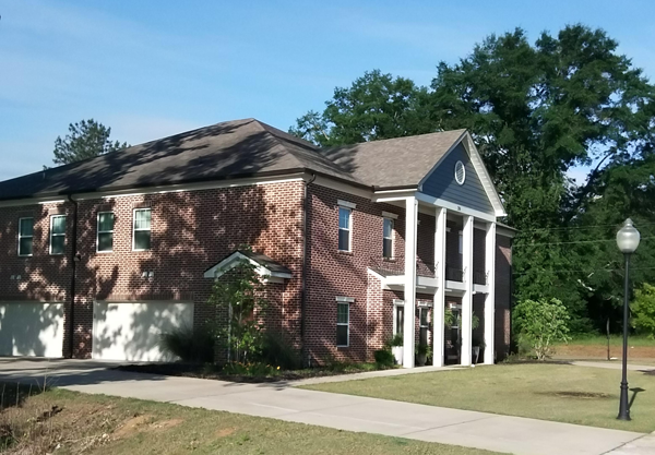 a red brick house with white columns and a black roof