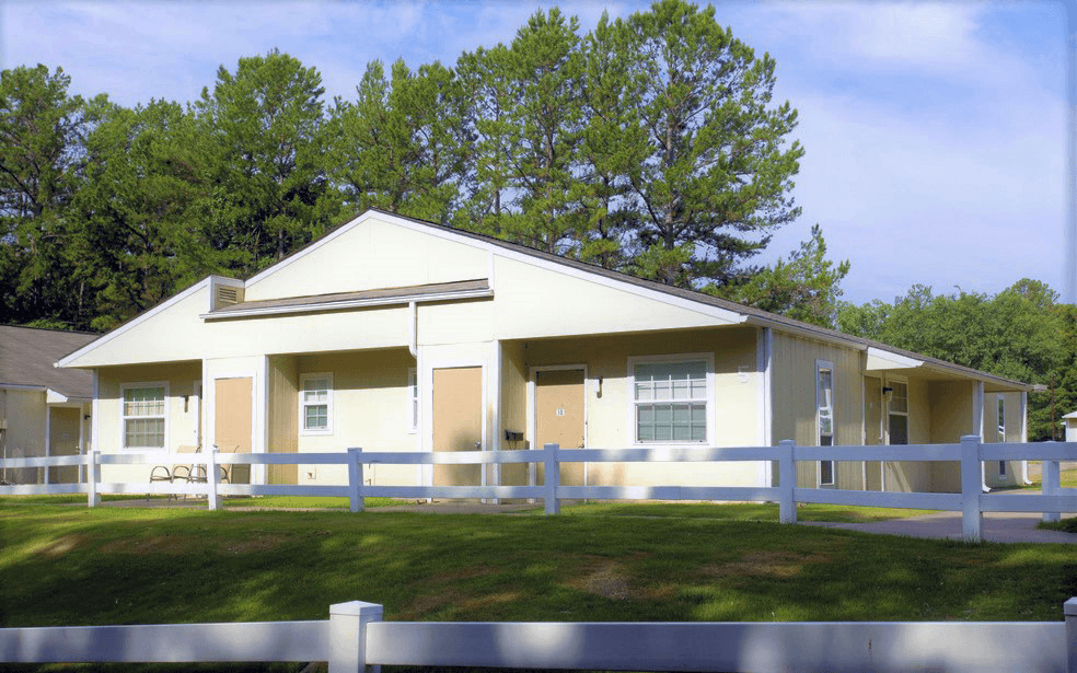 the front of a white house with a white fence