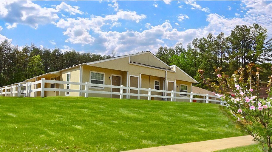 a yellow house with a white fence and green grass