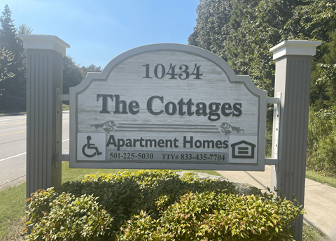 A sign for The Cottages Apartment Homes with a phone number and a TTY number.