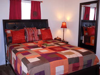 a bedroom with a bed with a colorful quilt