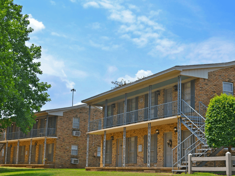 an exterior view of a brick building with a porch and a tree
