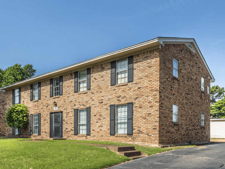 A red brick house with a green lawn in front.