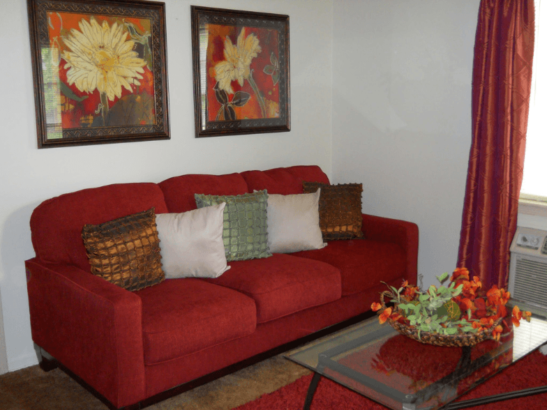 a red couch in a living room with paintings on the wall