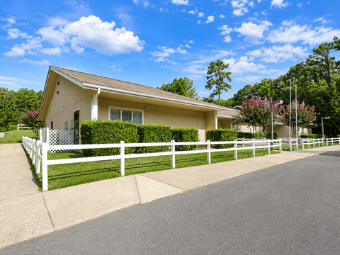 A house with a white fence and a driveway in front.