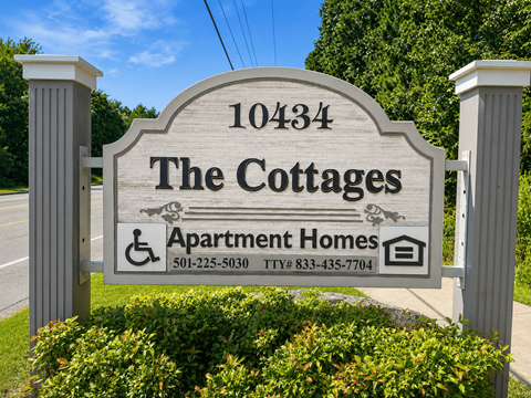 A sign for The Cottages Apartment Homes with a phone number and TTY number.