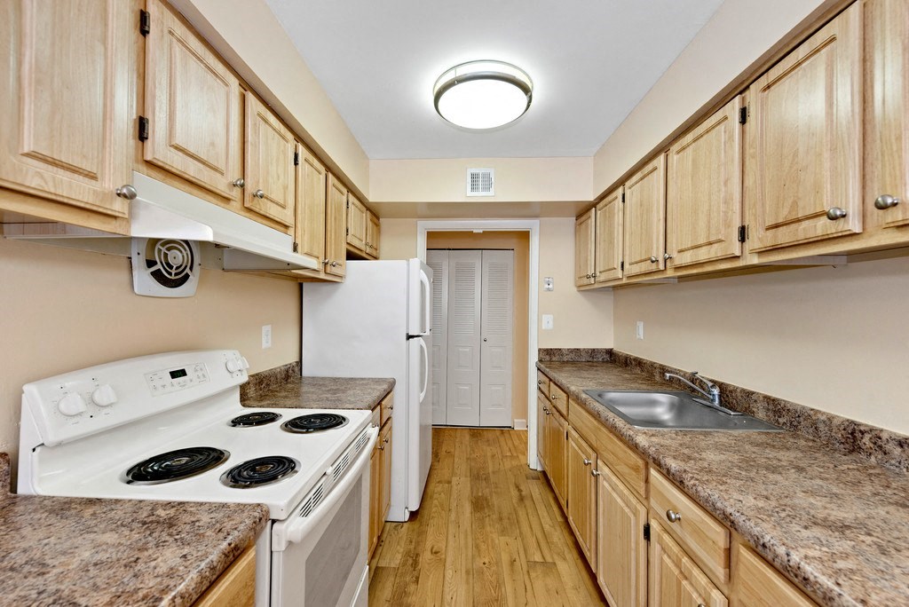 A kitchen with a white stove top oven and a white refrigerator.