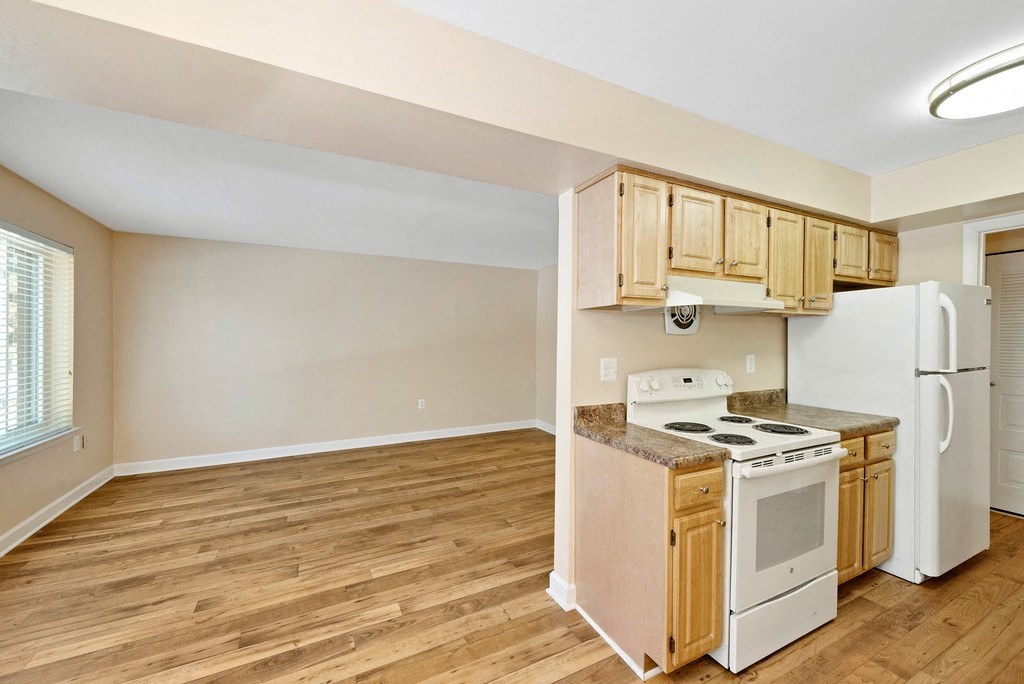 A kitchen with wooden floors and white appliances.