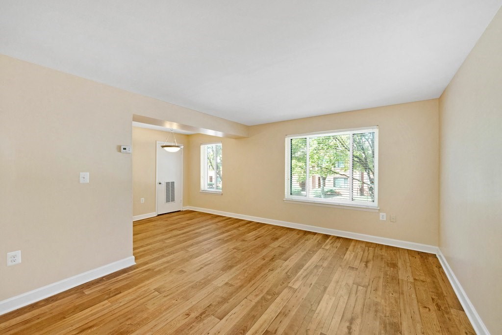 A room with wooden flooring and a window showing trees outside.