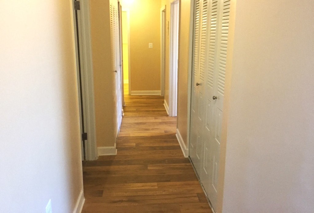 A long hallway with white walls and wood floors.