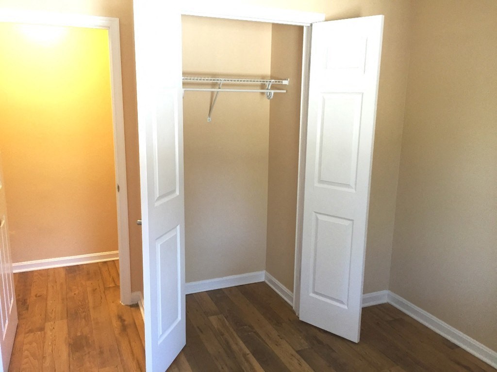 A white door is open to a room with a wooden floor.